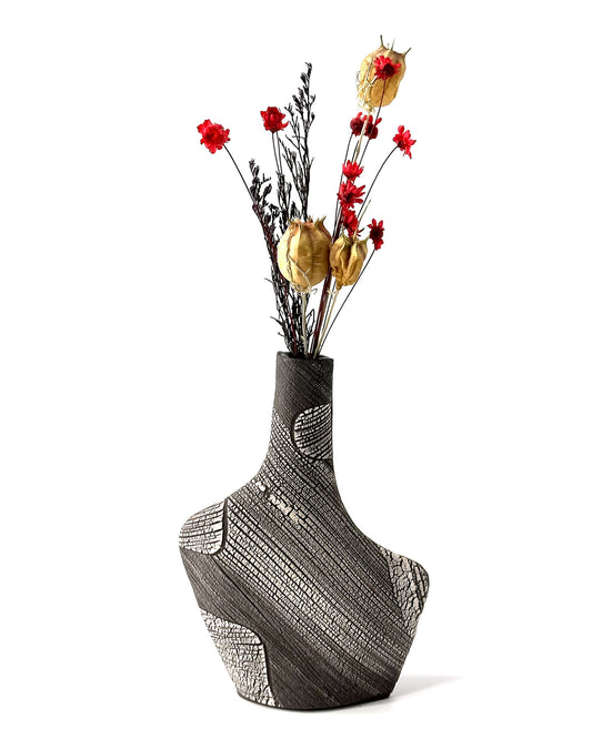 Decorative vase with intricate patterns and a bouquet of flowers on a white background