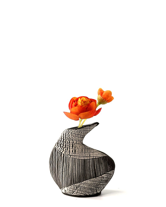 Decorative vase with wavy texture holding orange flowers on a white background